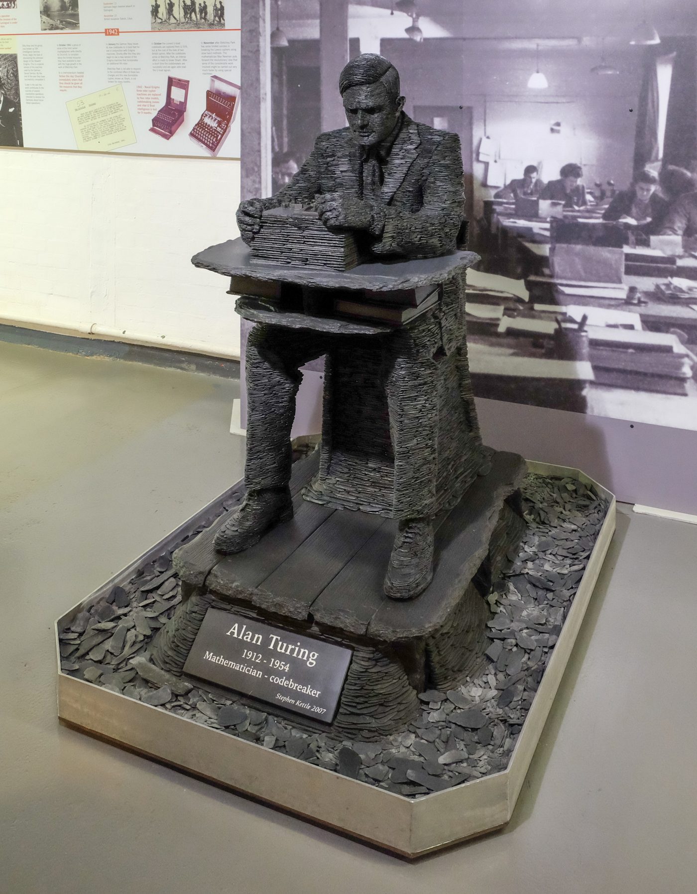 Figure 5 — The slate statue of Alan Turing by Stephen Kettle at Bletchley Park, built up from layers of Welsh slate. File:Alan Turing by Stephen Kettle 2007.jpg by DeFacto. License: CC BY-SA 4.0 (h…